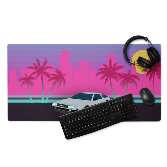 mouse pad with a neon pink miami cityscape on it. A DeLorean emblazons the middle and it is surrounded by palm trees. Vibrant pinks, blues are the main colours. A headset, mouse, and keyboard sits on top of the mousepad