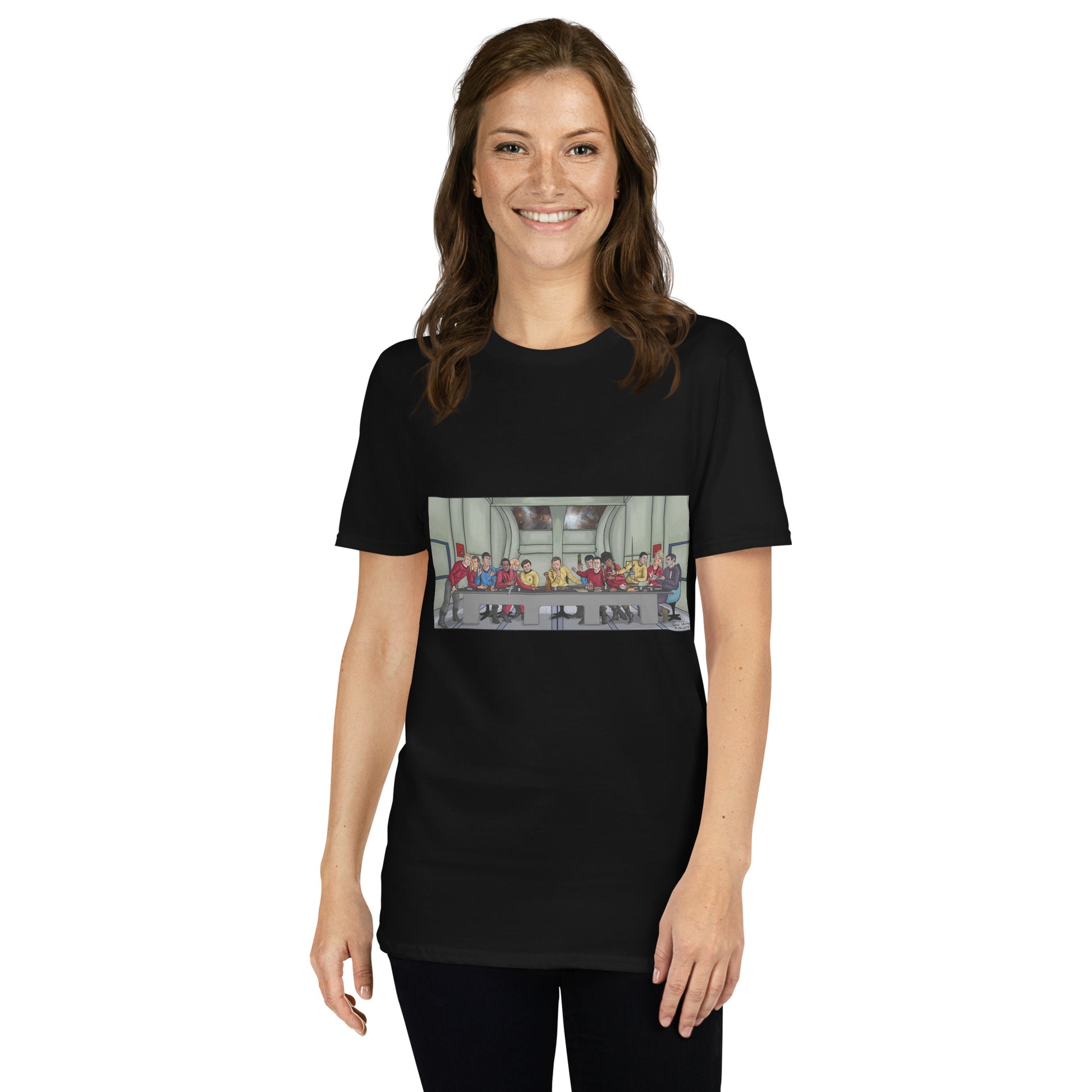 A white female poses casually wearing a black t-shirt with a rectangle image in the front centre that depicts The Last Supper painting by Michelangelo but done in cartoon style with the crew and cast of Star Trek the Original series depicted as the apostles and Jesus