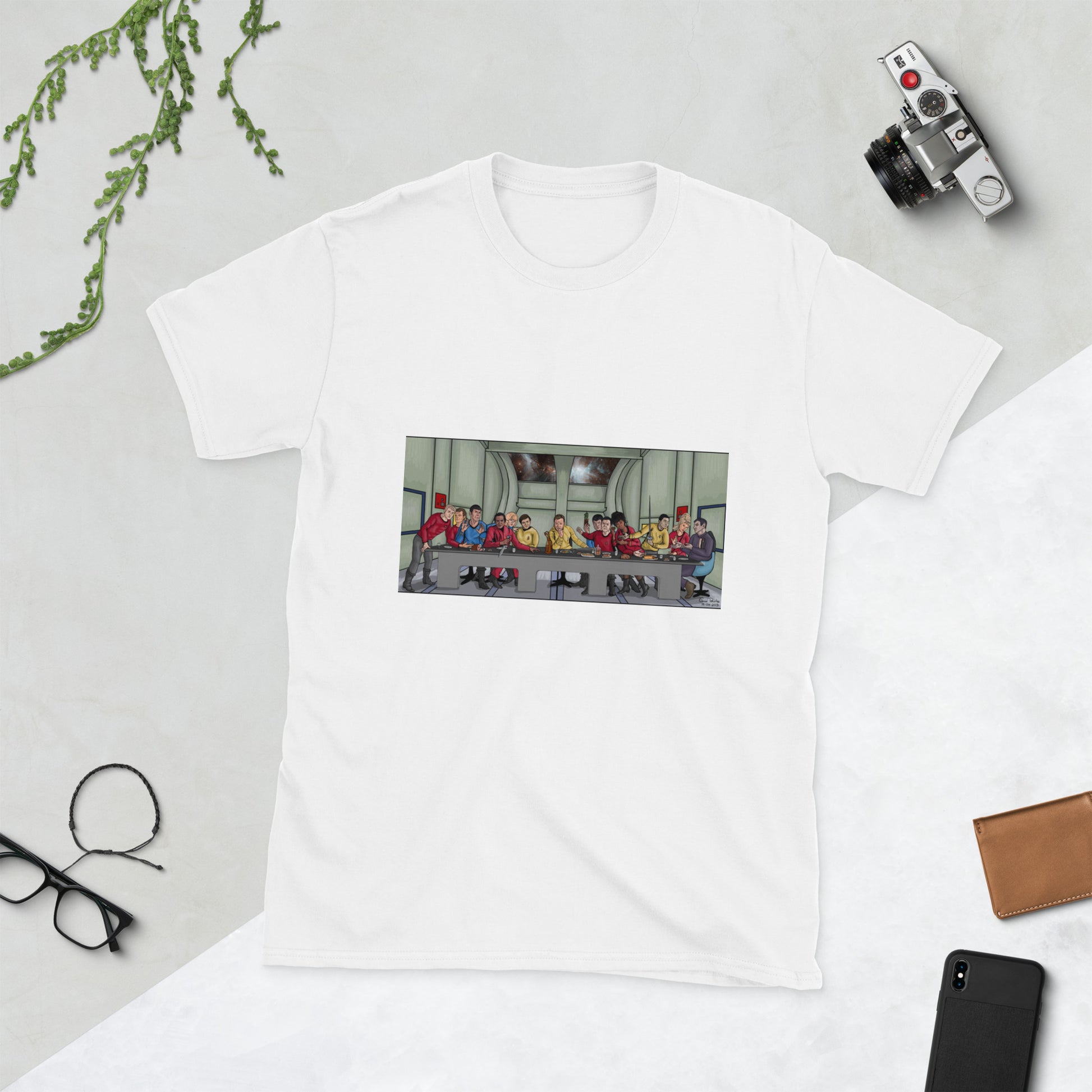 A white t-shirt with a rectangle image in the front centre that depicts The Last Supper painting by Michelangelo but done in cartoon style with the crew and cast of Star Trek the Original series depicted as the apostles and Jesus