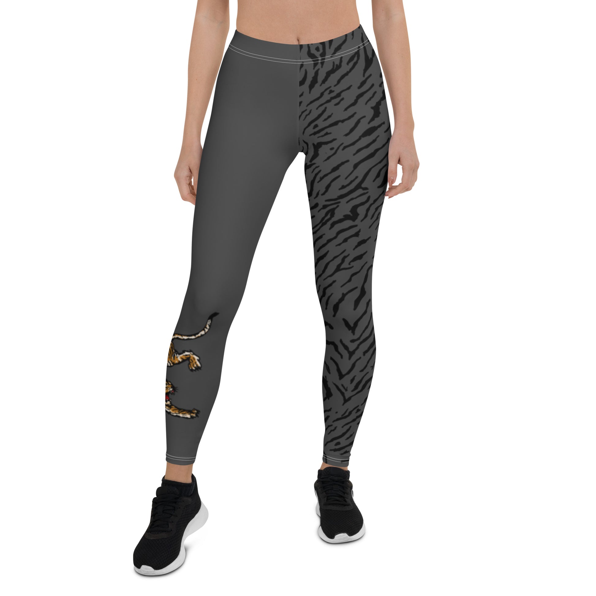 Female model wearing grey leggings with a hand drawn tiger on the right lower leg and black tiger print covers the left leg and waist fully on the left side, front and back.