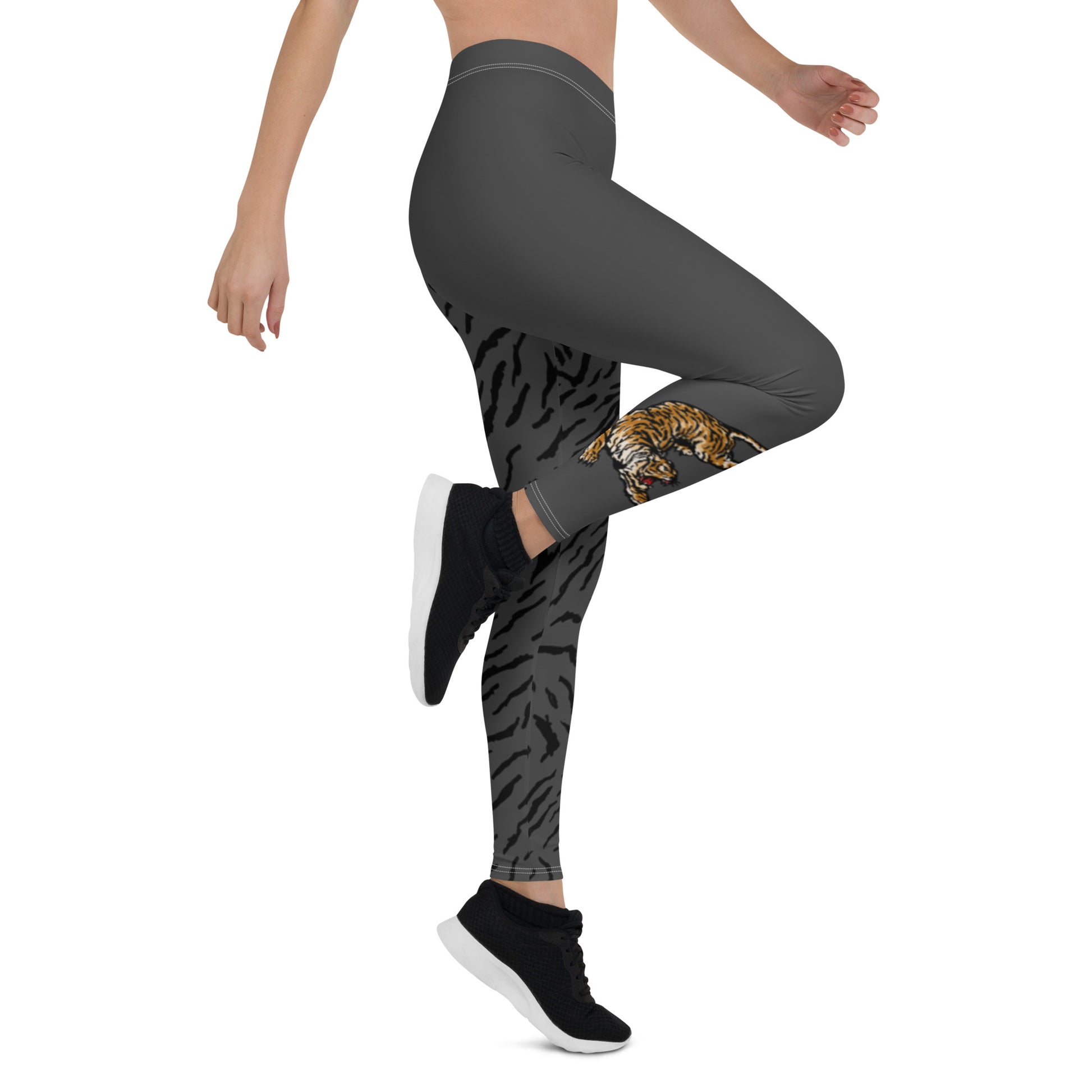 Female model wearing grey leggings with a hand drawn tiger on the right lower leg and black tiger print covers the left leg and waist fully on the left side, front and back.