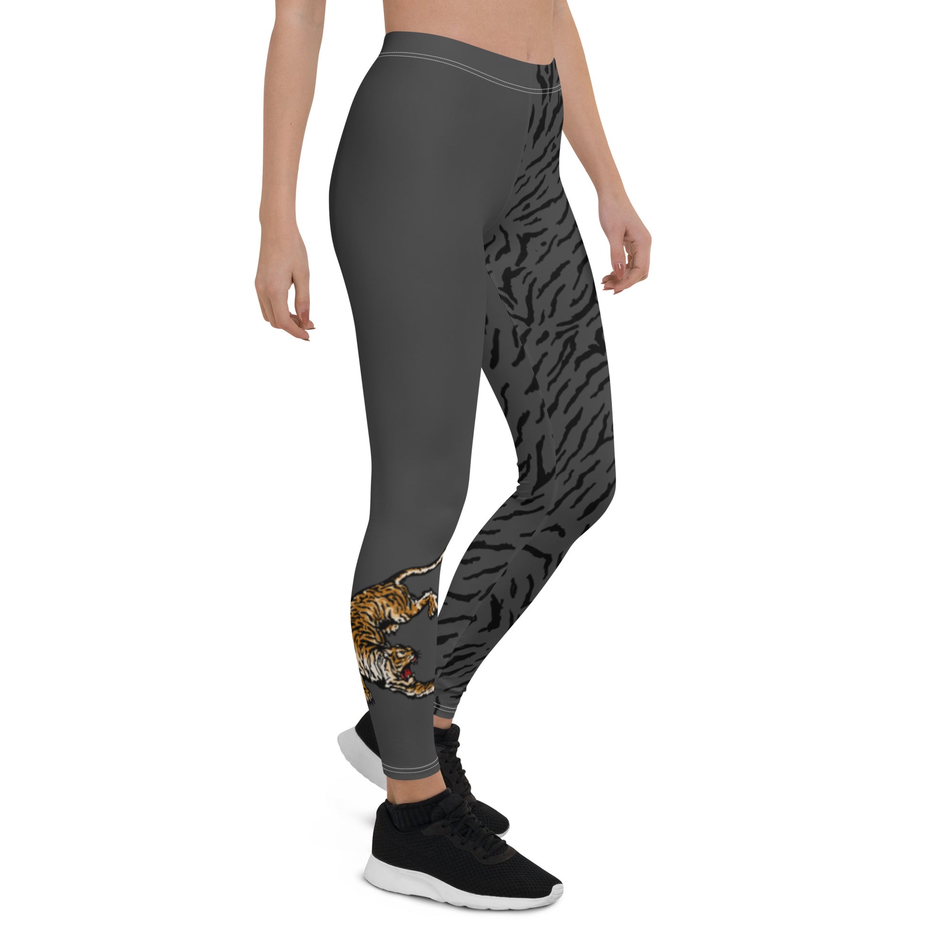 Female model wearing grey leggings with a hand drawn tiger on the right lower leg and black tiger print covers the left leg and waist fully on the left side, front and back.