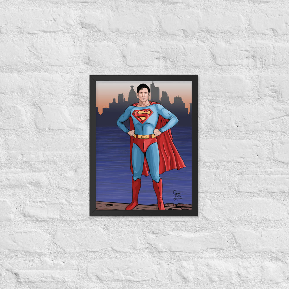 Semi realistic caricature of Christopher Reeve Superman standing on a dock with Metropolis in the background. The picture is framed with a black frame and is hanging on a white brick wall.