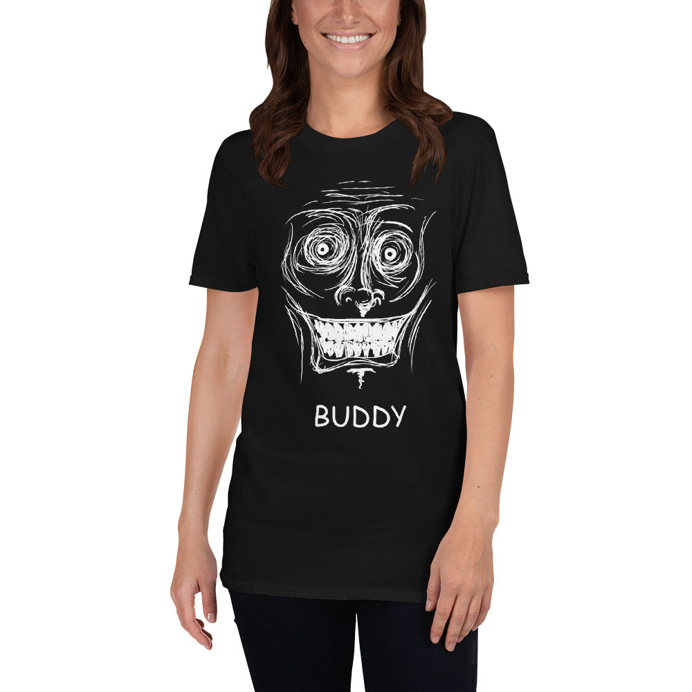 A white female stands in shot with a black t-shirt on that has a scribbled white line face with a inhumanely large grim grin on it's face. The word "BUDDY" is written in white underneath.